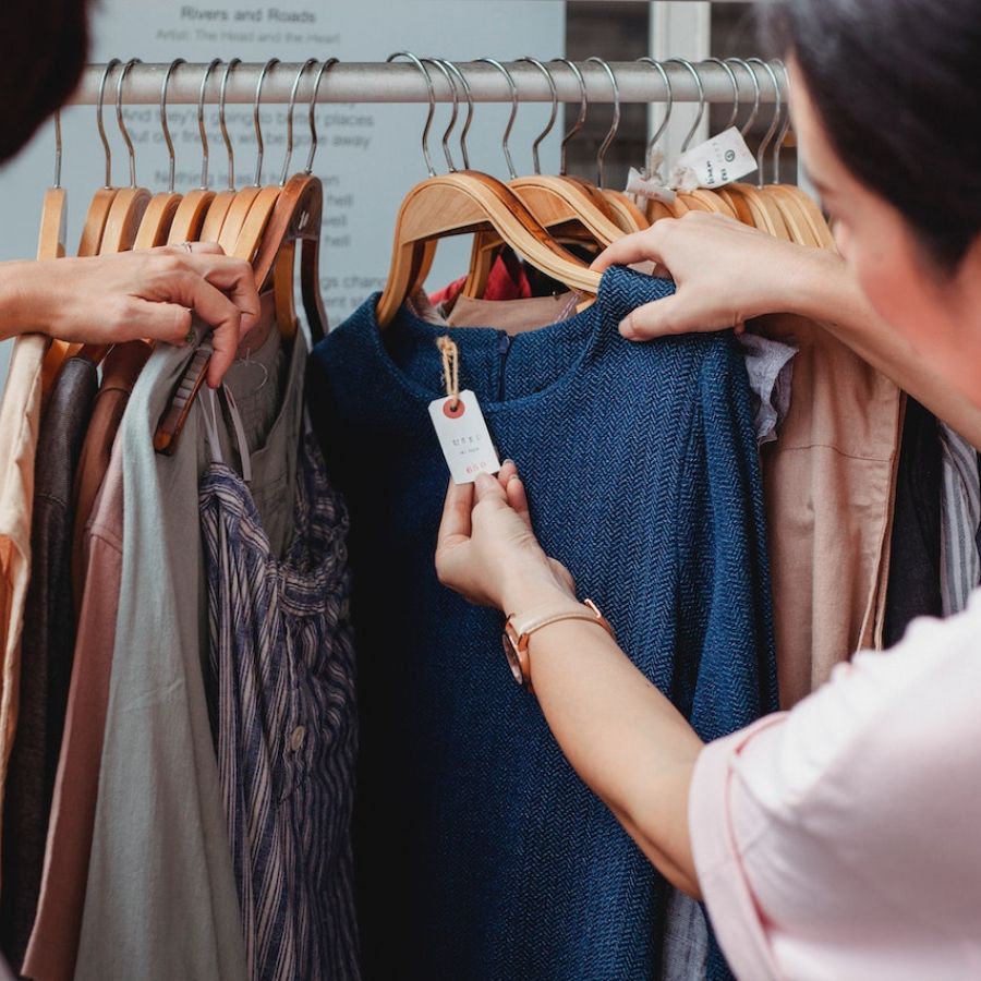Person inspecting price tag of clothing on rack